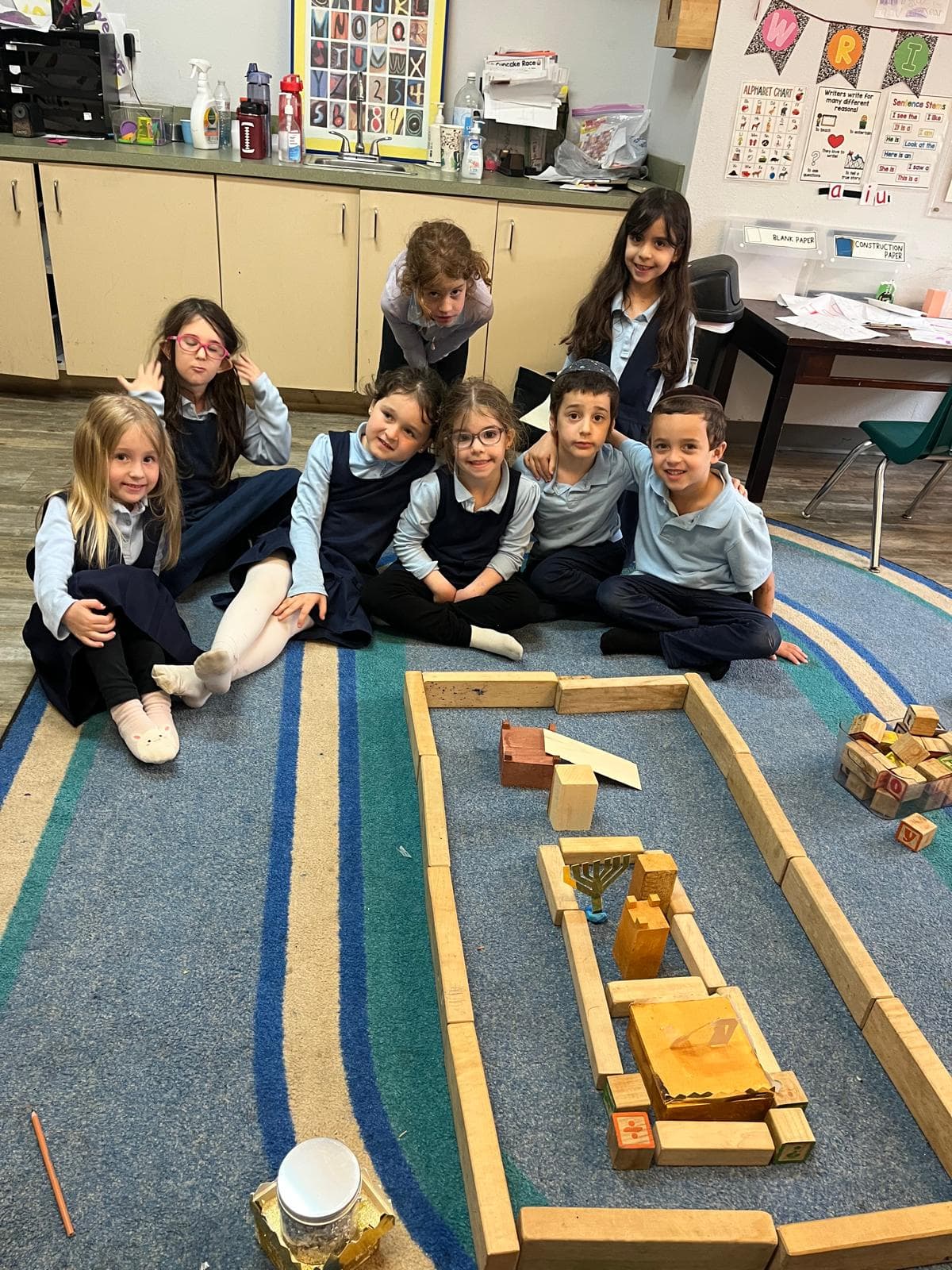 Students gathered around a block model of the Beis Hamikdash