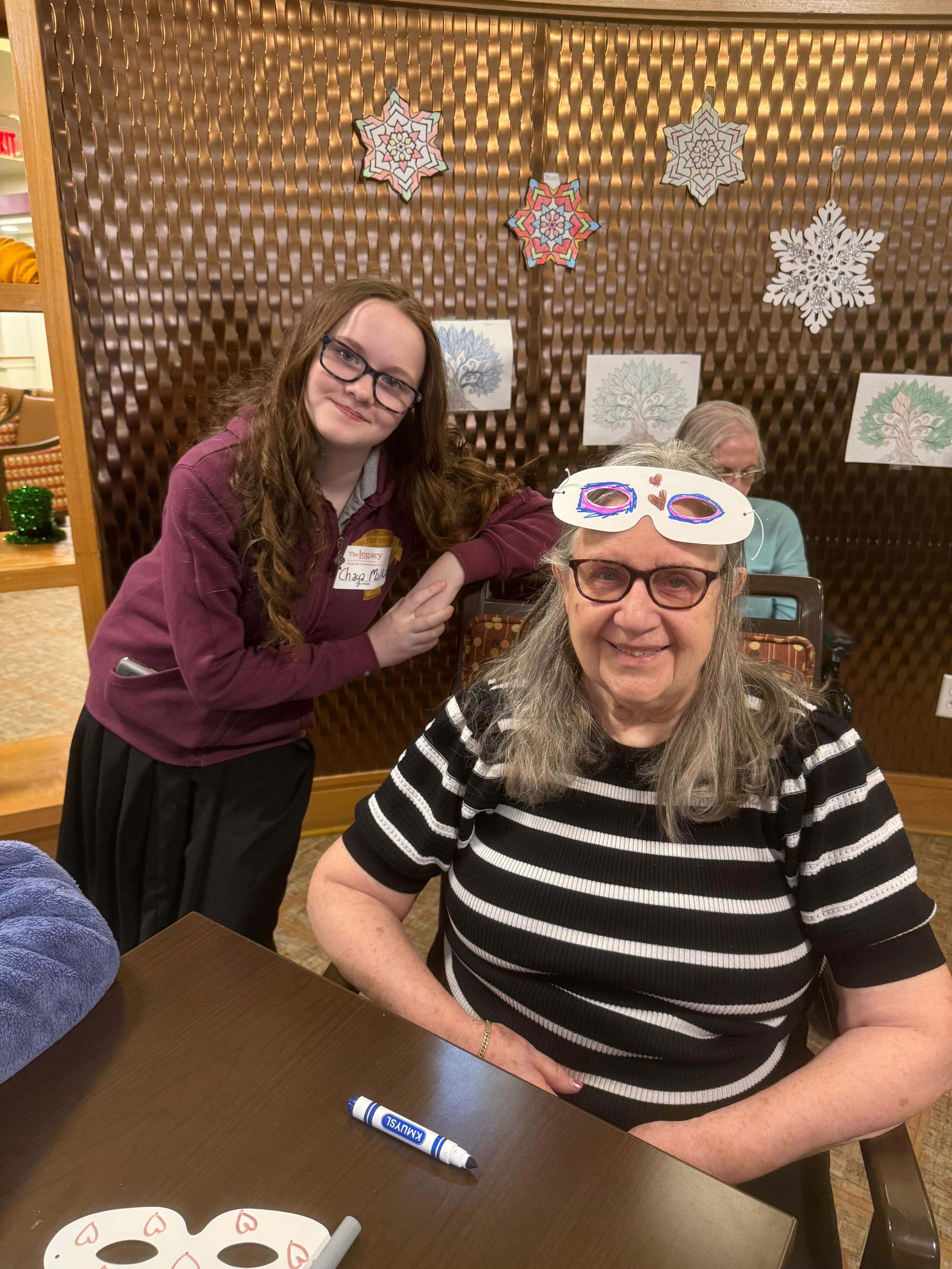 A student visiting and doing a craft with a senior resident